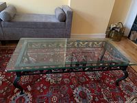 Top view of glass coffee table showing beveled glass edge and decorative metal base underneath.