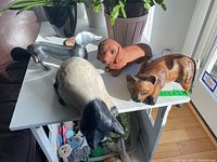 Four animal figures on a small table: metal dachshund, ceramic dachshund, and two carved wooden cats, all showing some wear.