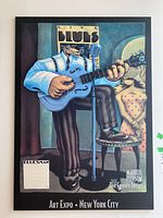 Full view of the mounted poster depicting a blues musician with guitar and a woman in polka dot dress, labeled with Markus Pierson The Coyote Series and Art Expo New York City