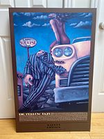 Full view of the mounted poster showing surreal artwork featuring a man in a striped suit and a woman on a vintage car with signage indicating 'Sublime'.