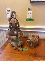 Photo showing a Mexican handmade figurine with detailed indigenous design and a smaller decorative teapot with floral ornamentation on a wooden table.