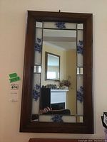 Full front view of rectangular mirror with wood frame and stained glass floral panels.