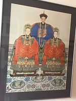 Front view of framed print showing three Asian figures dressed in traditional robes with ornate embroidery and headdresses, mounted with black matting inside simple black frame.