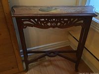 Full view of the vintage wooden side table showing carved legs, apron, and raised edges on top.