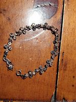 Full view of the assembled antique silver bracelet showing linked filigree star and cross charms with a spring clasp.