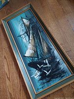 Full view of vintage sailboat oil on board painting in wooden frame with distinct green and gold trim