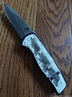 Close-up of the dagger blade partially open and wolf pack sculpted handle made of cultured stone.