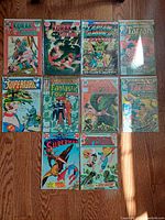 Lot of 11 vintage comic books laid out on floor including Korak Tarzan, Supergirl, Fantastic Four, Superman, and Tarzan titles