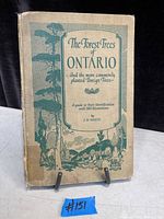 Front cover of the 1925 book titled 'The Forest Trees of Ontario and the More Commonly Planted Foreign Trees' by J.H. White, showing age wear and discoloration on beige cloth cover with green ink design.