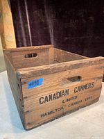 Photo of one wooden crate with visible Canadian Canners Limited 1961 branding, showing cutout handles and age wear.