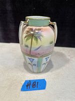Front view of the hand painted Nippon vase showing palm trees, sailboat, and floral pattern with gold accents on sides and handles.