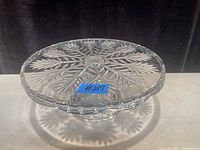 Top angled view of the clear crystal cake stand showing leaf pattern etching and scalloped edge.