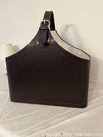 Brown leather-like large craft basket with strap handle, angled front view showing construction and exterior finish.
