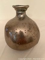 Jug-shaped brass-style small vase, 7.5 inches high, showing rounded body and narrow neck, speckled finish.