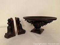 Photo of the carved wooden decorative bowl and a pair of matching carved wooden bookends on a white surface.
