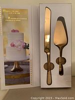 Cake cutter and lifter in original box with gold finish on stainless steel.