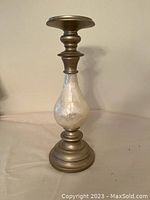 Brass finish candle holder with frosted glass element near base, tiered design