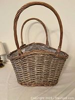 Large wicker basket with rounded handle and plastic liner visible inside