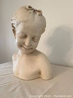Front view showing the smiling face, closed eyes, and upper torso of the young girl bust with detailed facial features and texture.