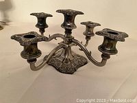 Silver-plated candelabra with five candle slots showing ornate details and overall condition.