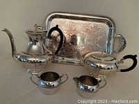 Group shot of silver plated set including coffee pot, tea pot, creamer, sugar bowl, and engraved serving tray