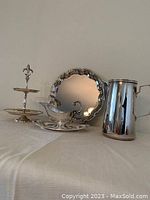 Photo showing entire silver plated serving set including tray, water jug, gravy boat with saucer, and two-tier dessert server with decorative finial