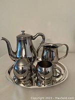 Photo showing the full coffee set arranged on the round tray including coffee pot, cream jug, sugar bowl with lid, and small container.