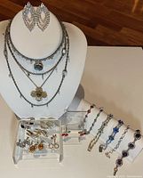 Full lot with necklaces displayed on bust, bracelets and earrings arranged on stands.
