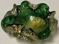Top view showing the ruffled edges, green color and gold flecks embedded inside the hand blown glass ashtray.
