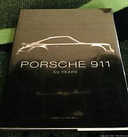 Front cover of the book with a black background and gold outline of a Porsche 911 car, the title and author name visible.