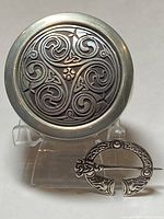 Photo of the Scottish pewter trinket box and the Celtic pin displayed on a stand.