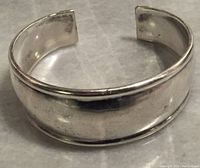 Front and top side view of the vintage sterling silver cuff bracelet showing open ends and smooth polished surface with some minor wear.