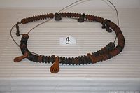 Full view of wooden beads strung on steel cable with numbered leather tabs, arranged in a circular pattern showing overall condition and structure.