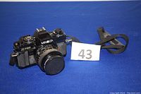 Full view of Minolta X-700 camera with strap on blue background and lot number.