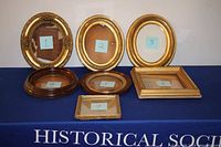 Seven antique picture frames displayed together on a blue cloth marked "HISTORICAL S".