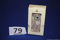Photo of the unopened Steiff jointed silver grey teddy bear in the original box with visible Steiff Club logo and ear button tag.