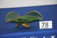 Side view of the green glass bonbon dish showing gold-edged scalloped rim and claw feet, with the Atlantic City 1902 marking visible.