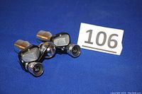 Two small vintage Tasco binoculars shown resting on a blue surface with lot number 106 nearby. Metal frame and eyepieces visible.