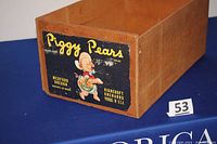Front closeup of the wooden crate showing the Piggy Pears label with cartoon pig and orchard info.