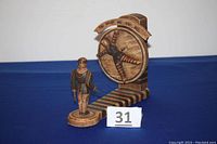 Front three-quarter view of music box and knife thrower figurine on blue background with numbered tag 31