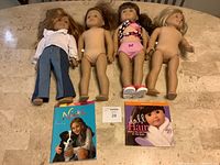 All four American Girl dolls laid out on table with two books shown below them.