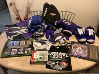 Full lot overview including slippers, jacket, T-shirt, plush figure, book bag and plaques on table