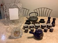 Photo showing Waterford crystal clock, crystal bowl, and clear ornate picture frame along with both tea sets on table.