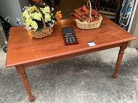 Full view of solid wood dining table with two floral baskets and Brookstone wine topper set on top