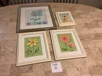 Four framed floral prints displayed on a table including various sizes and frames