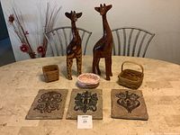 Photo showing two hand carved Jamaican giraffe figurines, three signed Longaberger baskets, and three Southern Living wall plaques on a table.
