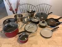 Full view of all kitchenware items on a table showing various pots, pans, lids, and mixing bowls