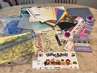 Photo showing entire assortment of scrapbooking materials including stencils, colored paper, stickers, embellishments, and tapes spread out on table