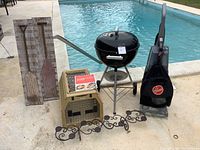 Photo showing Weber grill, Hoover vacuum, pet carrier, candleholder, and wall art by poolside