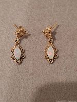 Close-up image showing front side of earrings with the marquise-shaped opal stones set in intricate gold filigree settings, highlighting the color play in the opals.